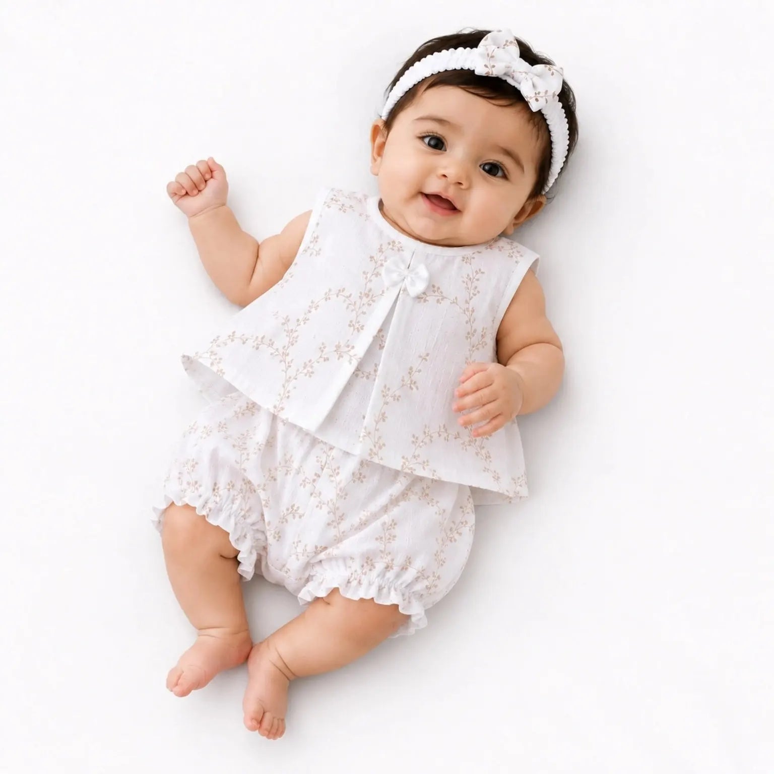 Baby girl wearing white floral muslin frock, matching bloomer and hairband