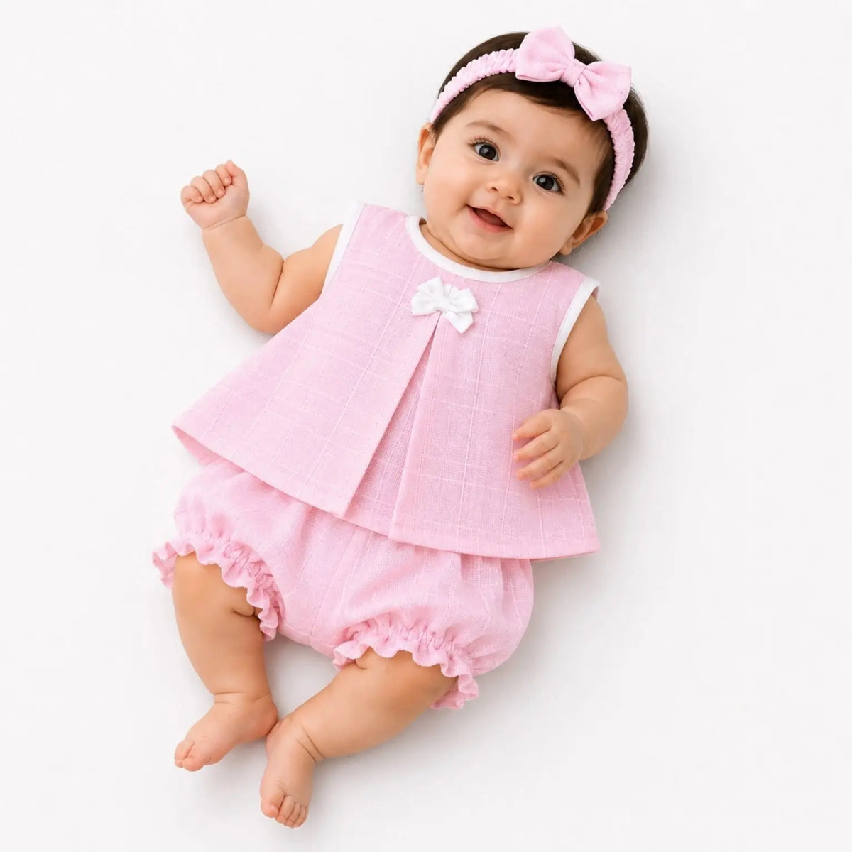 Baby girl wearing pink muslin frock, matching bloomer and hairband