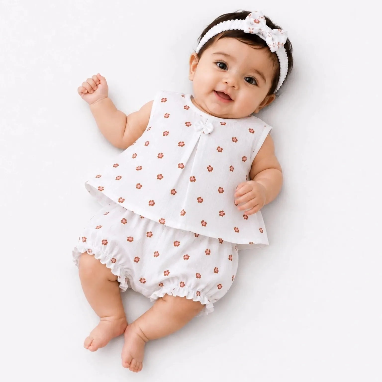 Baby girl wearing white muslin frock, matching bloomer and hairband with orange print