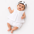 Baby girl wearing plain white muslin frock, matching bloomer and hairband