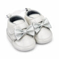 Metallic silver baby girl first walker shoes with decorative bow, hook and loop strap and soft sole – angled view