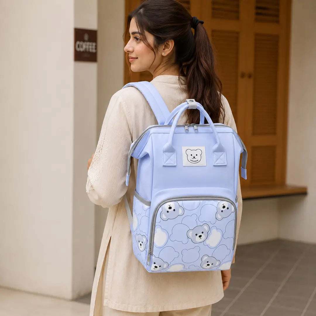 Light blue baby diaper bag backpack with bear print worn by mother