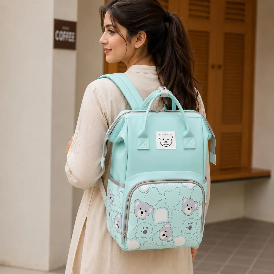 Mint green baby diaper bag backpack with bear print worn by mother