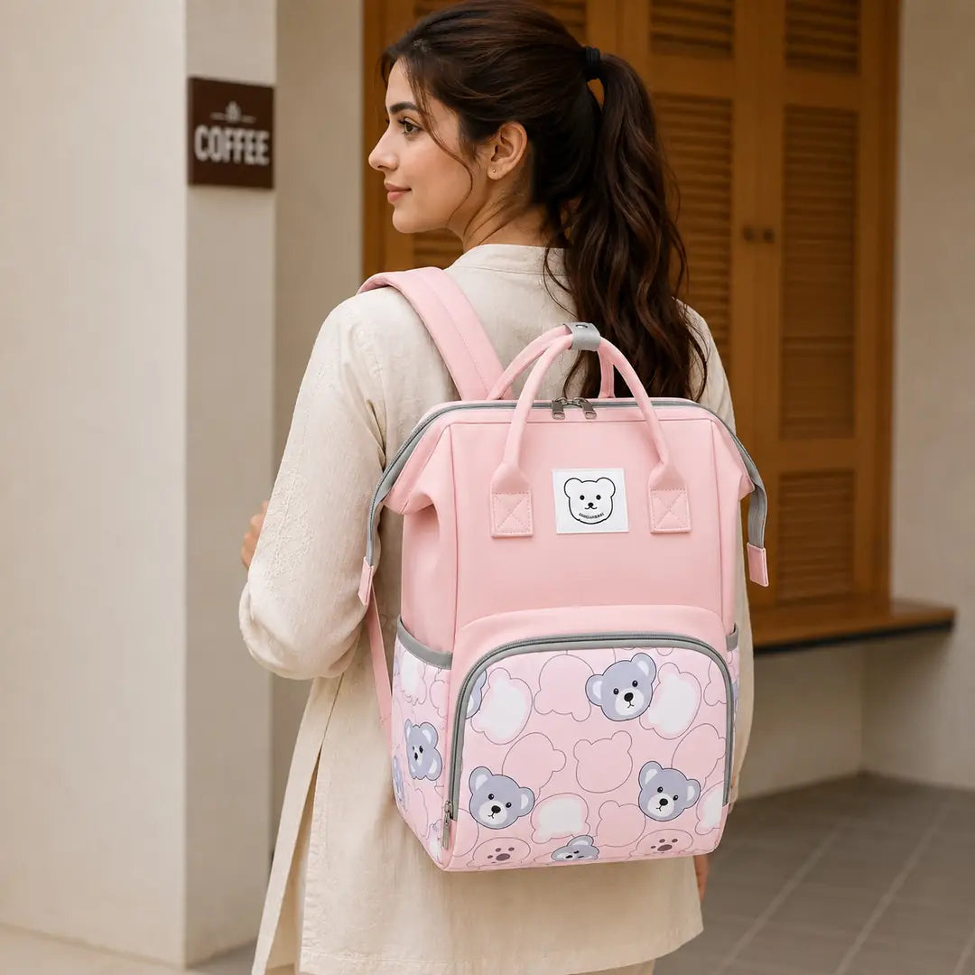 Pink baby diaper bag backpack with bear print worn by mother
