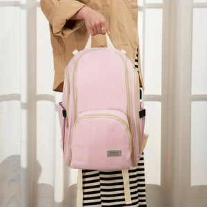 Pink baby diaper backpack held by top handle in a bright lifestyle setting