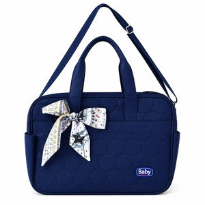 Navy blue quilted baby diaper bag with bow design and carry handles