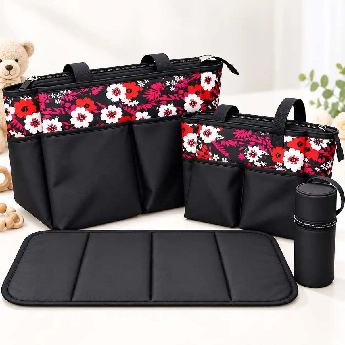 4-piece black floral baby diaper bag set with red, pink and white flower print, two diaper bags, bottle holder and padded changing mat
