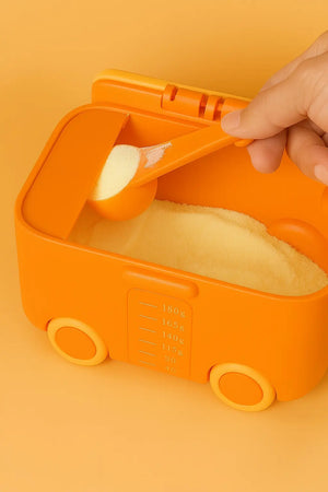 Orange formula storage box showing powder compartment and built-in scraper