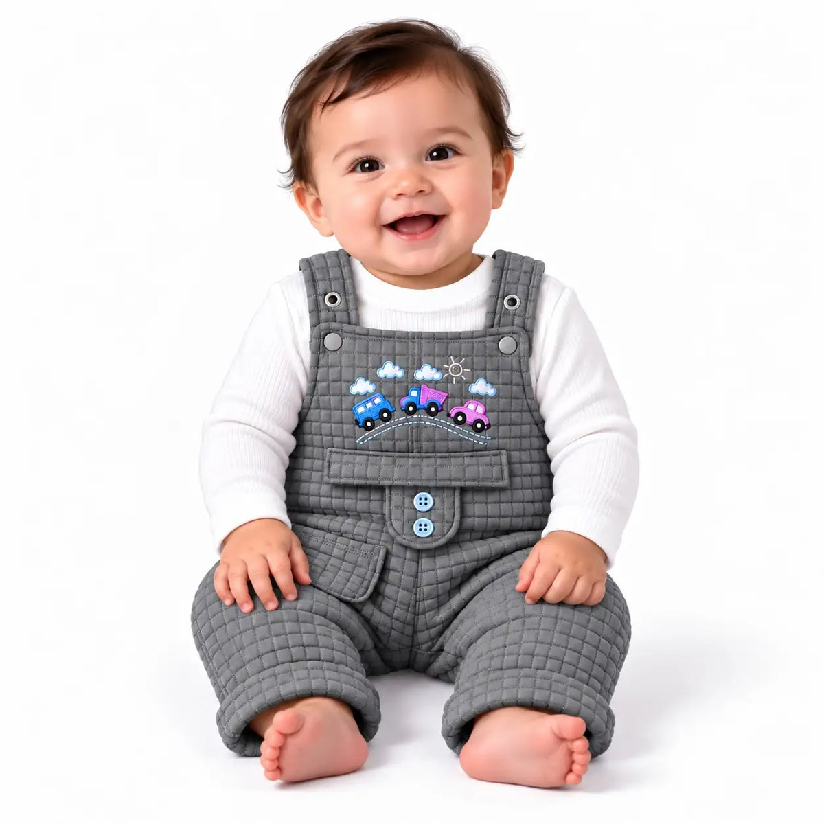 Smiling baby wearing grey quilted dungaree romper with white inner shirt and colorful embroidered cars