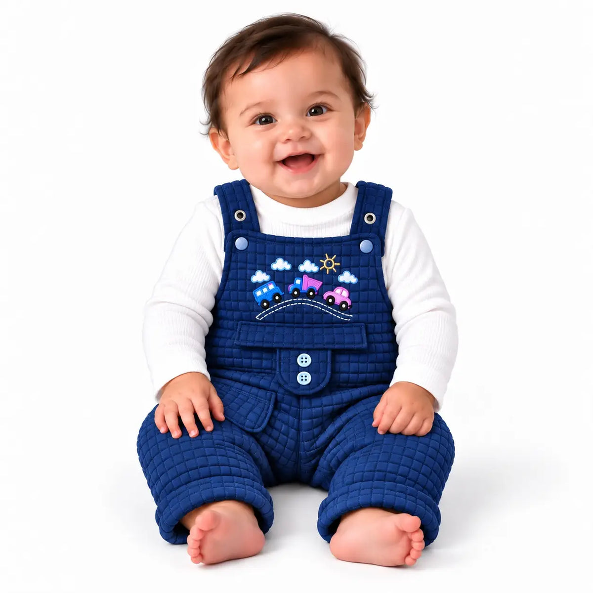 Smiling baby wearing navy blue quilted dungaree romper with white ribbed inner shirt and colorful embroidered cars