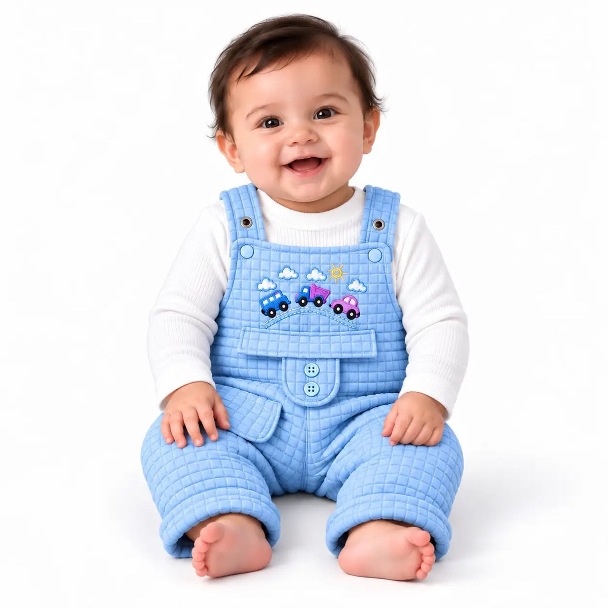 Smiling baby wearing sky blue quilted dungaree romper with white ribbed inner shirt and colorful embroidered cars