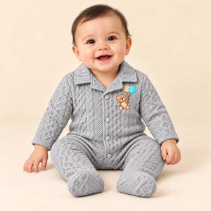 Baby wearing light grey winter quilted footed romper with teddy bear embroidery and textured cable-style pattern in seated pose