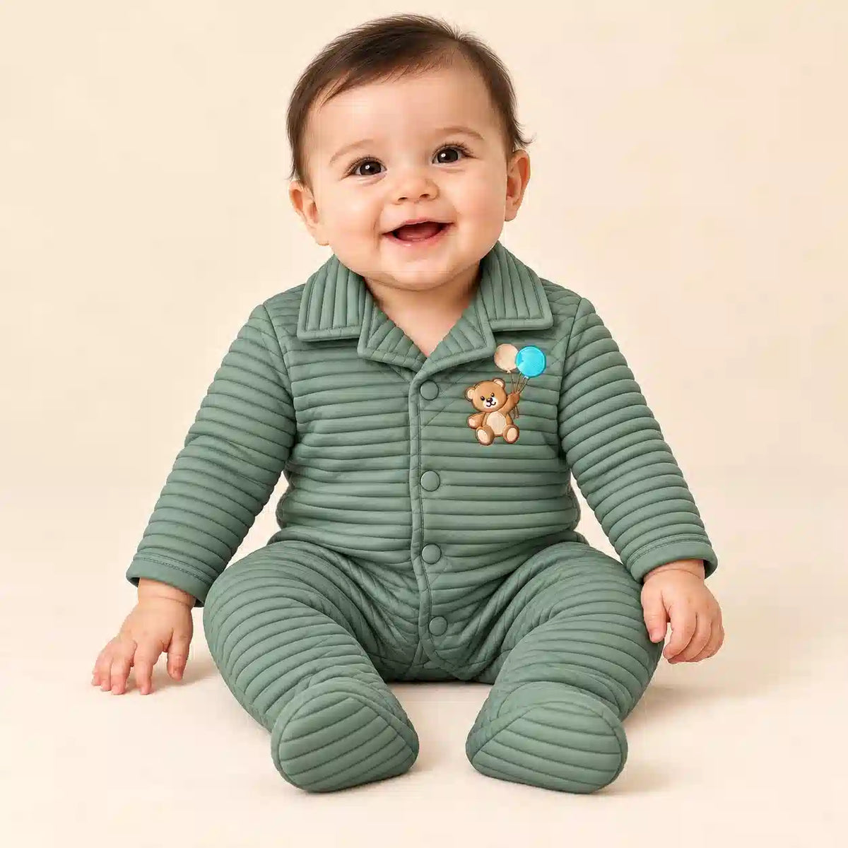 Baby wearing sage green winter ribbed quilted footed romper with teddy bear embroidery in seated pose