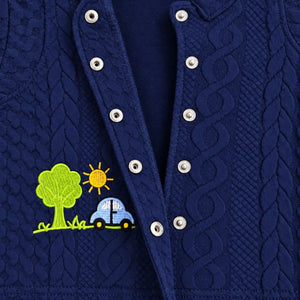 Close-up of open metal snap buttons and car and tree embroidery on navy blue textured baby shirt