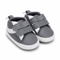 Side-angle view of baby boys grey and white soft sole double strap shoes