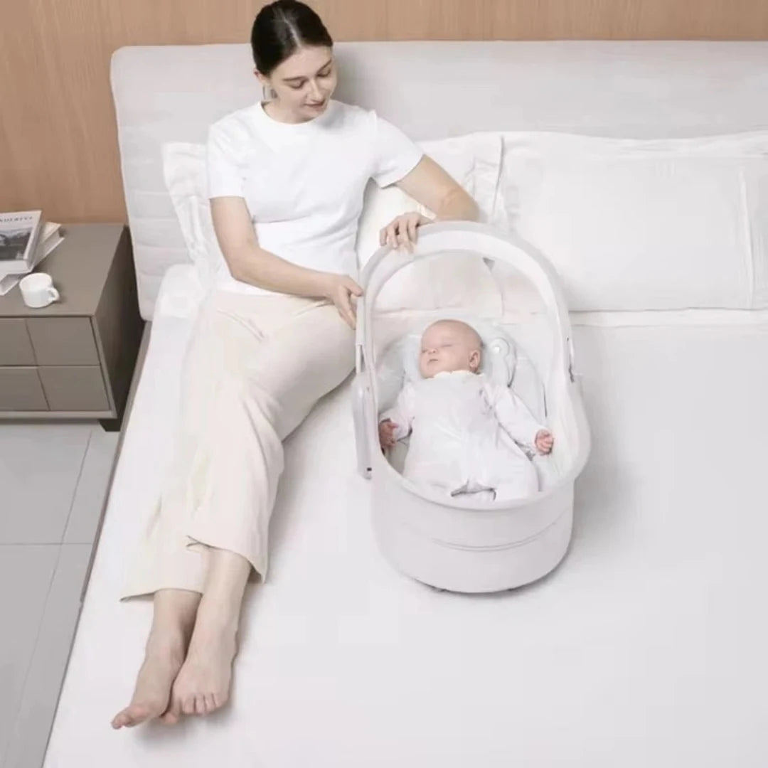 Mastela 09877 baby bassinet beside a bed for newborn resting