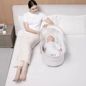 Mastela 09877 baby bassinet beside a bed for newborn resting