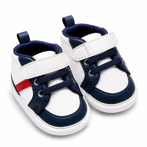 White and navy blue casual baby shoes with red side accent angled view