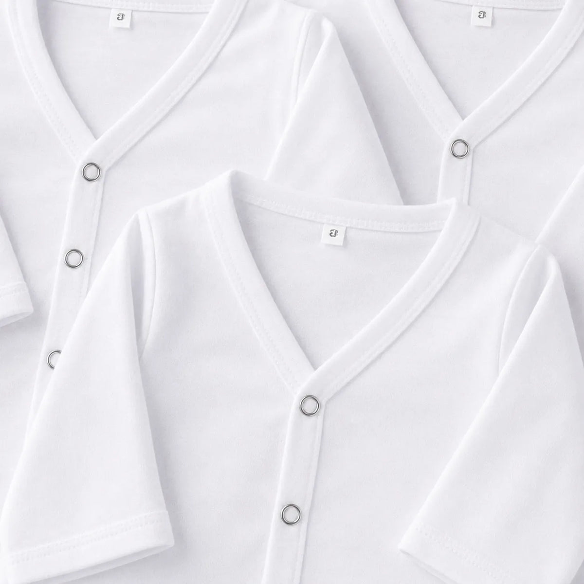 Newborn baby white front open shirt snap button and fabric close-up