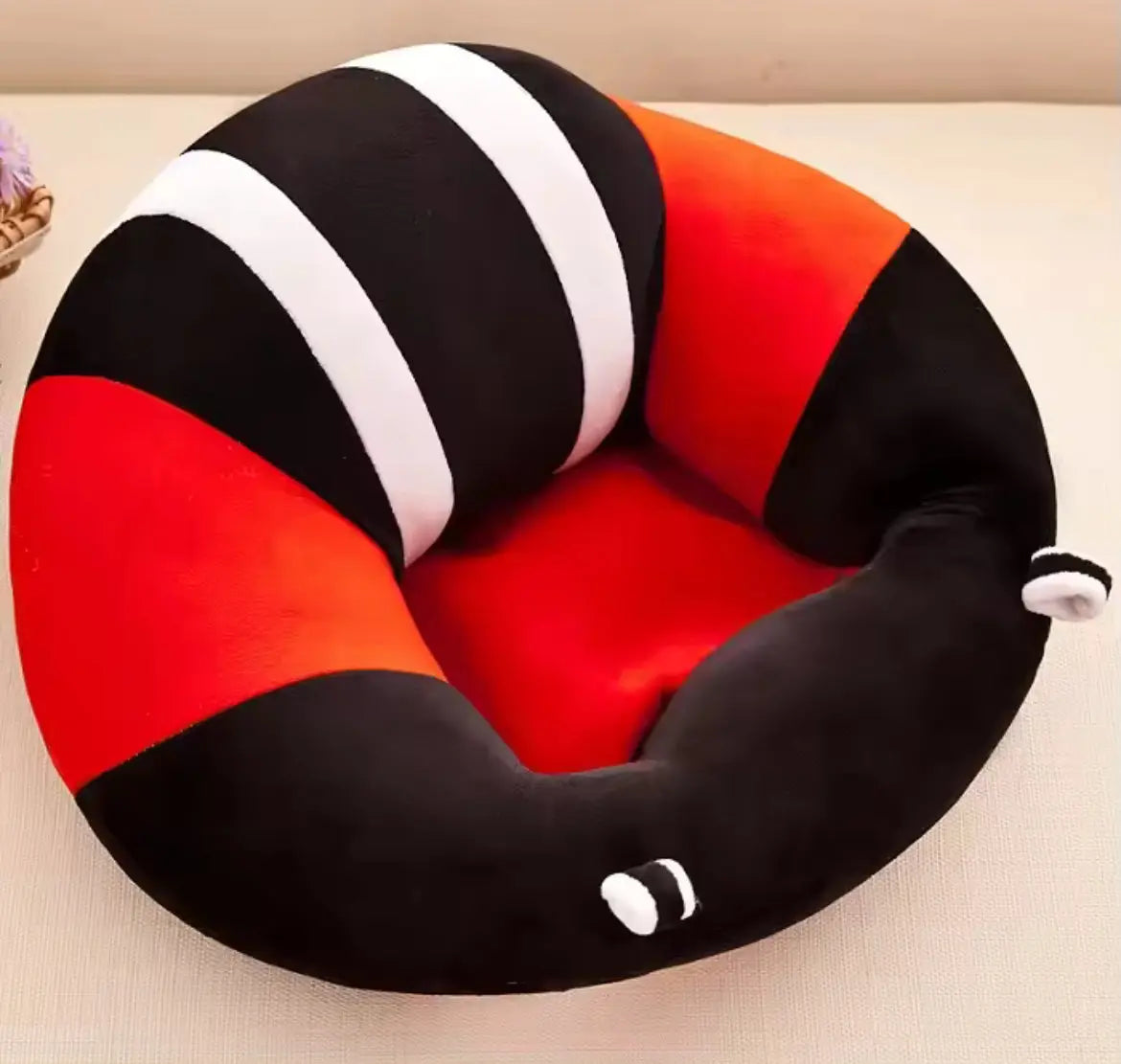 Angled view of red and black plush baby sitting support chair