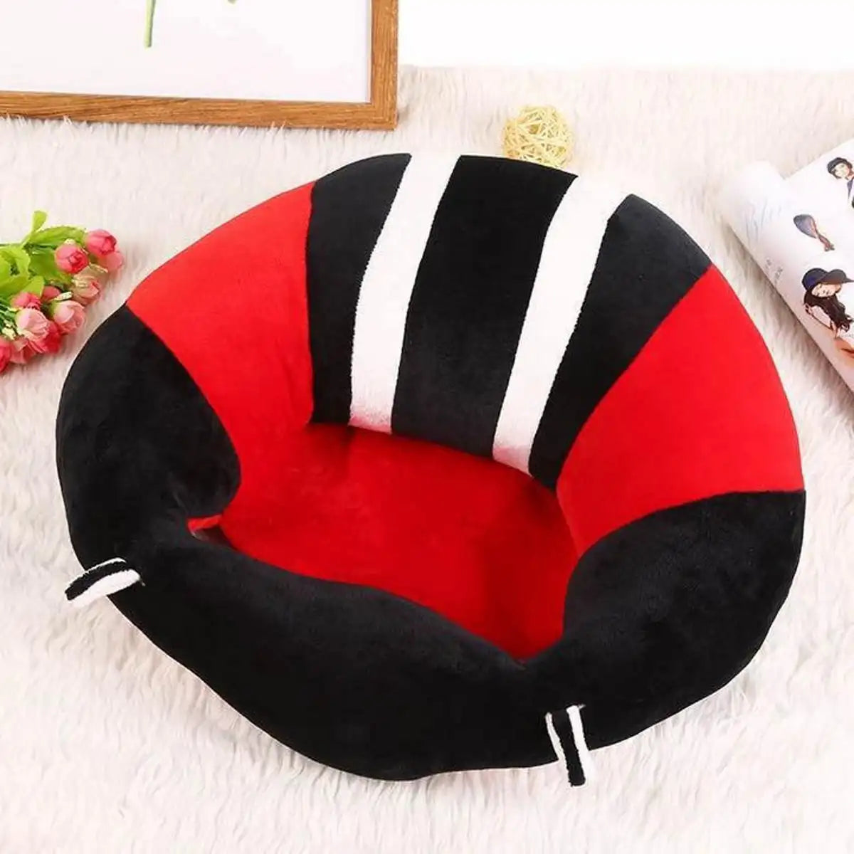 Red and black plush baby sitting chair shown in an indoor setting