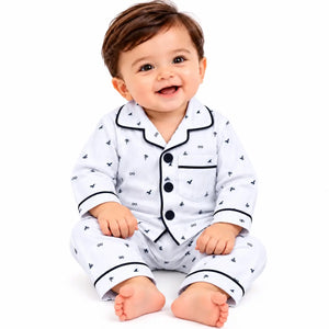 Baby wearing a white mini print night suit with dark contrast piping, long sleeves and a chest pocket